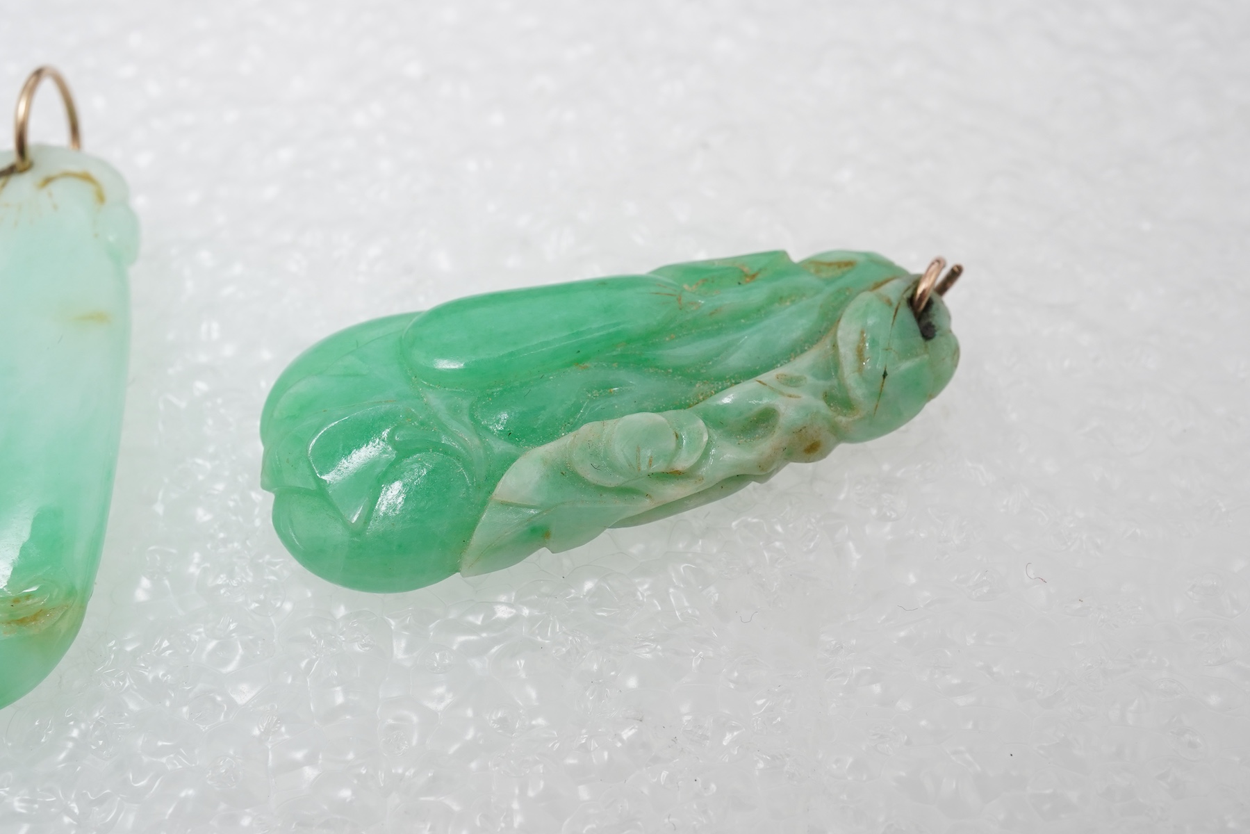 Two carved jadeite pendants, China, early 20th century, each carved to depict a fruiting vine of bitter gourd, longest 3.5cm excluding bail, combined gross weight approximately 10 grams